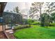 A screened in pool sits among green grass, mulch beds, and mature trees in this spacious backyard at 2712 Arugula Dr, North Port, FL 34289