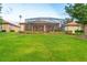 A spacious backyard has green grass and garden beds that lead to the screened in lanai with a pool at 2712 Arugula Dr, North Port, FL 34289