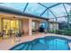 A screened in pool with tanning ledge is bordered by outdoor seating with views of the house and backyard at 2712 Arugula Dr, North Port, FL 34289