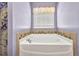Close up of a bathtub with tile surround, and window with blinds at 27896 Arrowhead Cir, Punta Gorda, FL 33982
