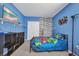 Bright blue bedroom featuring a fun accent wall, carpeted floors, and shelving at 27896 Arrowhead Cir, Punta Gorda, FL 33982