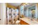 Bathroom features wood cabinets, decorated mirror, toilet, and bathtub with decorative shower curtain at 3308 Purple Martin Dr # 121, Punta Gorda, FL 33950