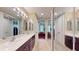Bright bathroom features double sinks, dark cabinets, decorative rug, and mirrors on closet doors at 3308 Purple Martin Dr # 121, Punta Gorda, FL 33950