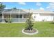 Manicured backyard with green grass, decorative tree, bird bath and screened-in patio at 388 Orlando Blvd, Port Charlotte, FL 33954