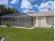 Manicured backyard with green grass, decorative tree, bird bath and screened-in patio at 388 Orlando Blvd, Port Charlotte, FL 33954
