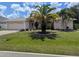 Inviting home with a lush lawn, mature palm trees, and an attached two-car garage at 388 Orlando Blvd, Port Charlotte, FL 33954