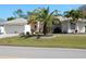 Charming single-story home featuring a well-manicured lawn, mature palm trees, and a two-car garage at 388 Orlando Blvd, Port Charlotte, FL 33954