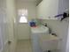 Functional laundry room with a utility sink, white cabinets, and a window for natural light at 388 Orlando Blvd, Port Charlotte, FL 33954