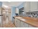 Neutral kitchen with butcher block countertops, gray cabinets, stainless steel dishwasher and view of hall at 4062 Blitzen Ter, North Port, FL 34287