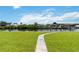 Grassy backyard with a charming pathway leading to a canal and a covered boat dock at 4123 Rock Creek Dr, Port Charlotte, FL 33948