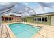This backyard shows the screened in pool area with stone tile and a convenient grab rail for pool entry at 4123 Rock Creek Dr, Port Charlotte, FL 33948