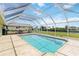 A covered screened-in pool area with lounge seating, and travertine tile overlooking the backyard and canal at 4123 Rock Creek Dr, Port Charlotte, FL 33948