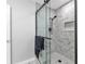 Bathroom with a tiled shower, a glass door, marble floors, and a white door at 4244 Harbor Blvd, Port Charlotte, FL 33952