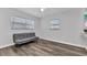 Bedroom with hardwood floors, two windows with blinds, a ceiling fan, and a gray couch at 4244 Harbor Blvd, Port Charlotte, FL 33952