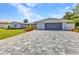 Home exterior featuring an attached garage with a gray brick driveway and a well-manicured front yard at 4244 Harbor Blvd, Port Charlotte, FL 33952