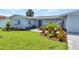 Charming single-story home featuring a beautifully landscaped front yard with colorful plants and fresh green grass at 4244 Harbor Blvd, Port Charlotte, FL 33952