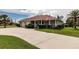 Inviting home featuring a manicured lawn, long driveway, attached garage, and cozy front porch at 437 South Dr, Punta Gorda, FL 33950