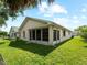 Rear exterior view showcases a screened-in lanai overlooking the manicured lawn at 464 Rose Apple Cir, Port Charlotte, FL 33954