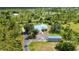Expansive property with a light blue-roofed house, storage shed, and asphalt driveway surrounded by lush greenery at 5950 Cypress Grove Cir, Punta Gorda, FL 33982