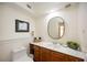 Cozy bathroom with a toilet, a vanity and an oval mirror above the sink at 5950 Cypress Grove Cir, Punta Gorda, FL 33982