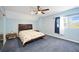 Cozy bedroom featuring blue walls, a ceiling fan, and natural light from the window at 5950 Cypress Grove Cir, Punta Gorda, FL 33982