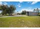 Landscaped front yard with large metal storage building, circular driveway, and mature trees at 5950 Cypress Grove Cir, Punta Gorda, FL 33982