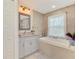 Well-lit bathroom featuring gray cabinets, granite countertops, and a luxurious built-in bathtub at 6444 Alhambra Ave, North Port, FL 34291