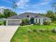 Charming single-story home featuring a manicured lawn, lush landscaping, and a two-car garage at 6444 Alhambra Ave, North Port, FL 34291