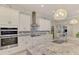 Modern kitchen with stainless steel appliances, white cabinets, and a stylish gray backsplash and granite countertops at 6444 Alhambra Ave, North Port, FL 34291