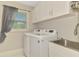 Bright laundry room featuring a modern washer and dryer, a utility sink, and storage cabinets at 6444 Alhambra Ave, North Port, FL 34291