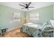 Bedroom with a floral patterned bed, ceiling fan, wood flooring, windows, and mint-colored walls at 1027 Coral Ridge Dr, Punta Gorda, FL 33950