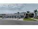 Condominium exterior with private garages, tropical landscaping, and paver driveway under partly cloudy skies at 12390 Wellen Golf St # 202, Venice, FL 34293