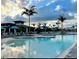 A stunning resort-style swimming pool with palm trees, lounge chairs, and umbrellas under a cloudy sky at 12390 Wellen Golf St # 202, Venice, FL 34293