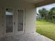 Covered patio with brick pavers and double glass doors entering the home at 136 Sequoyah Dr, Port Charlotte, FL 33954