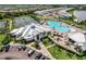 Aerial view of a modern community center, a shimmering swimming pool, and parking spaces, surrounded by manicured lawns and trees at 14141 Heritage Landing Blvd # 921, Punta Gorda, FL 33955