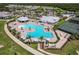 Aerial view of a resort-style community pool with sun loungers, palm trees, and clear blue water, accompanied by tennis courts at 14141 Heritage Landing Blvd # 921, Punta Gorda, FL 33955