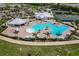 Aerial view of a luxury community pool with ample seating, palm trees, and a splash pad surrounded by lush landscaping at 14141 Heritage Landing Blvd # 921, Punta Gorda, FL 33955