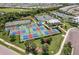 Aerial view of community pickleball and tennis courts amidst lush greenery and landscaping, complemented by a stylish clubhouse at 14141 Heritage Landing Blvd # 921, Punta Gorda, FL 33955