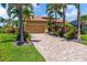 Charming home with a paver driveway, lush tropical landscaping, and a well-manicured lawn, creating an inviting curb appeal at 170 Antilla Dr, Rotonda West, FL 33947