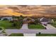 An aerial view of a home at sunset features a well-manicured yard, mature landscaping, and water views at 170 Antilla Dr, Rotonda West, FL 33947