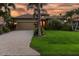Well-maintained home with a paver driveway, lush landscaping, and a welcoming entrance, set against a picturesque sunset at 170 Antilla Dr, Rotonda West, FL 33947