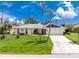 Charming single-story home with a well-manicured lawn, mature trees, and a two-car garage at 18147 Brazil Ave, Port Charlotte, FL 33948