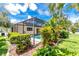 Landscaped backyard featuring a screened pool area with privacy hedges and tropical plants at 18147 Brazil Ave, Port Charlotte, FL 33948