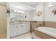Elegant bathroom featuring a large soaking tub and a vanity with a large mirror at 2329 Como St, Port Charlotte, FL 33948