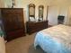 Bedroom with tropical bedding, wood dresser with mirrors and armoire, adjacent to the bathroom at 25228 E Lenox Cir, Punta Gorda, FL 33950