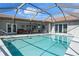 Large swimming pool with screened enclosure next to a covered patio featuring a dining table and comfortable seating at 2814 La Mancha Ct, Punta Gorda, FL 33950