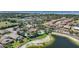Aerial view of homes with tile roofs nestled among mature trees and a sparkling community pool and lake at 3631 Pebble Ter, Punta Gorda, FL 33980