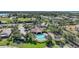 Aerial view of a community pool and clubhouse surrounded by palm trees, lush lawns, and mature trees at 3631 Pebble Ter, Punta Gorda, FL 33980