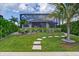 Landscaped backyard with stepping stones, lush lawn, screen enclosure and manicured hedges and palm trees at 3800 Carupano Ct, Punta Gorda, FL 33950