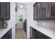 Chic butler's pantry featuring gray cabinets, white countertops, tile backsplash, and access to the laundry room at 3800 Carupano Ct, Punta Gorda, FL 33950